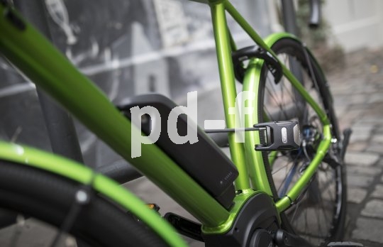 Ein grünes E-Bike, mit einem Faltschloss angeschlossen.