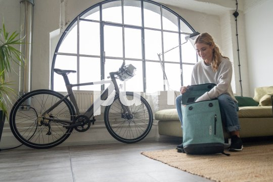 Frau packt Fahrradrucksack in Wohnung