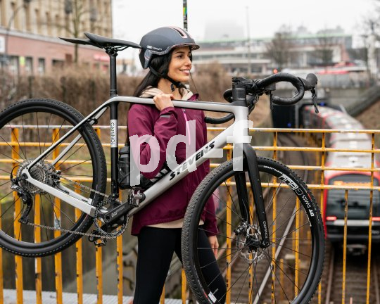 Frau trägt Fahrrad über Brücke