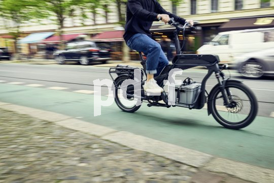 Mensch fährt beladenes Cargobike durch die Stadt.