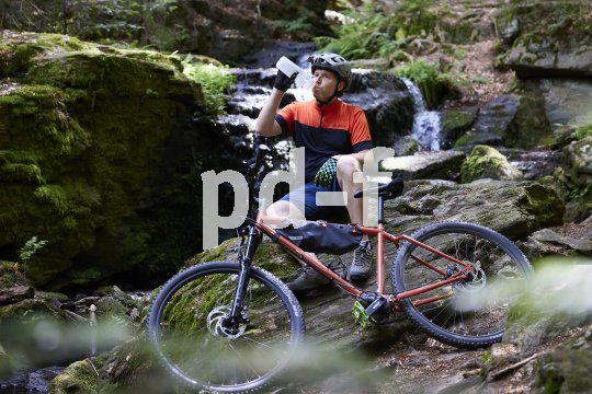 Mountainbiker sitzt vor Wasserfall