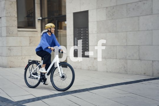 Frau fährt auf E-Bike durch eine Stadt.
