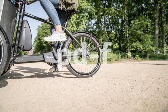 Ein E-Lastenrad in einem Park, halb im Bild.