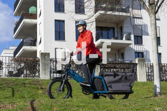 Frau fährt Lastenrad für Wohnhaus