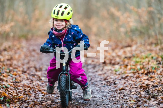 Kind fährt mit Laufrad im Wald