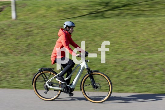 Frau fährt mit E-Bike vor Wiese