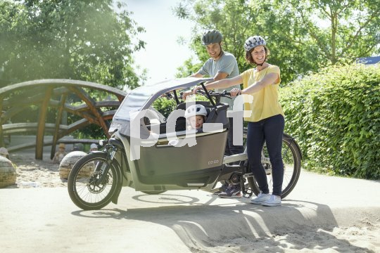 Familie mit Lastenrad auf Spielplatz