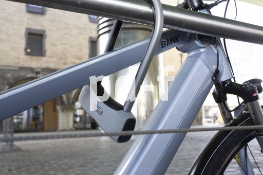 Ein Bügelschloss sichert ein Fahrrad mit dem Rahmen an einem Geländer.