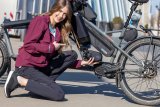 Eine Frau kniet vor einem E-Lastenrad und präsentiert einen E-Bike-Motor.