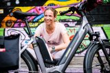 Eine Frau sitzt lächelnd hinter einem abgestellten E-Bike.
