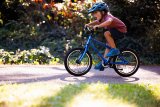 Ein Kind fährt ein blaues Fahrrad.