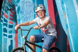 Ein Kind auf einem BMX-Rad vor Graffiti. 