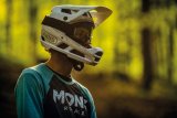 Mann trägt Fullface-Helm in Wald beim Mountainbiken.