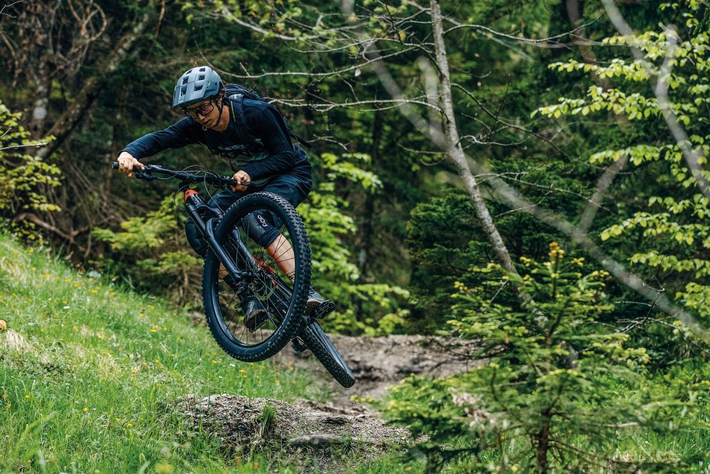 Mann springt mit Mountainbike über Hindernis. 