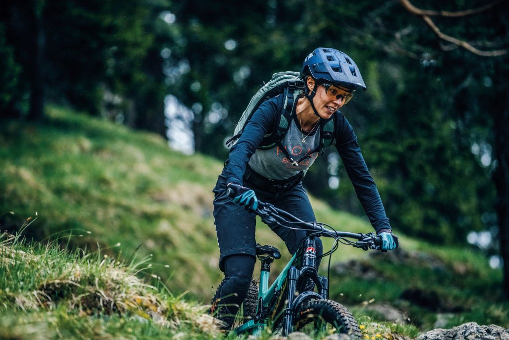 Frau fährt mit Mountainbike über Wiese.