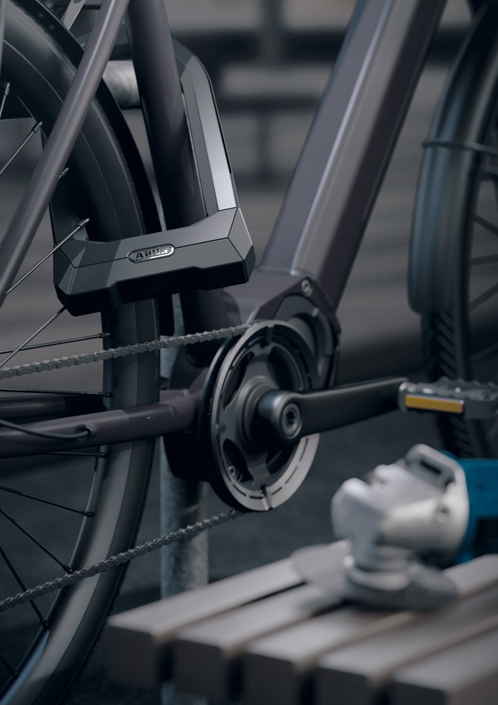 Ein Fahrrad ist mit dem Bügelschloss Granit Super Extreme 2500 von ABUS an einem Fahrradständer angeschlossen. Im Vordergrund liegt ein Trennschleifer  auf einer Bank.