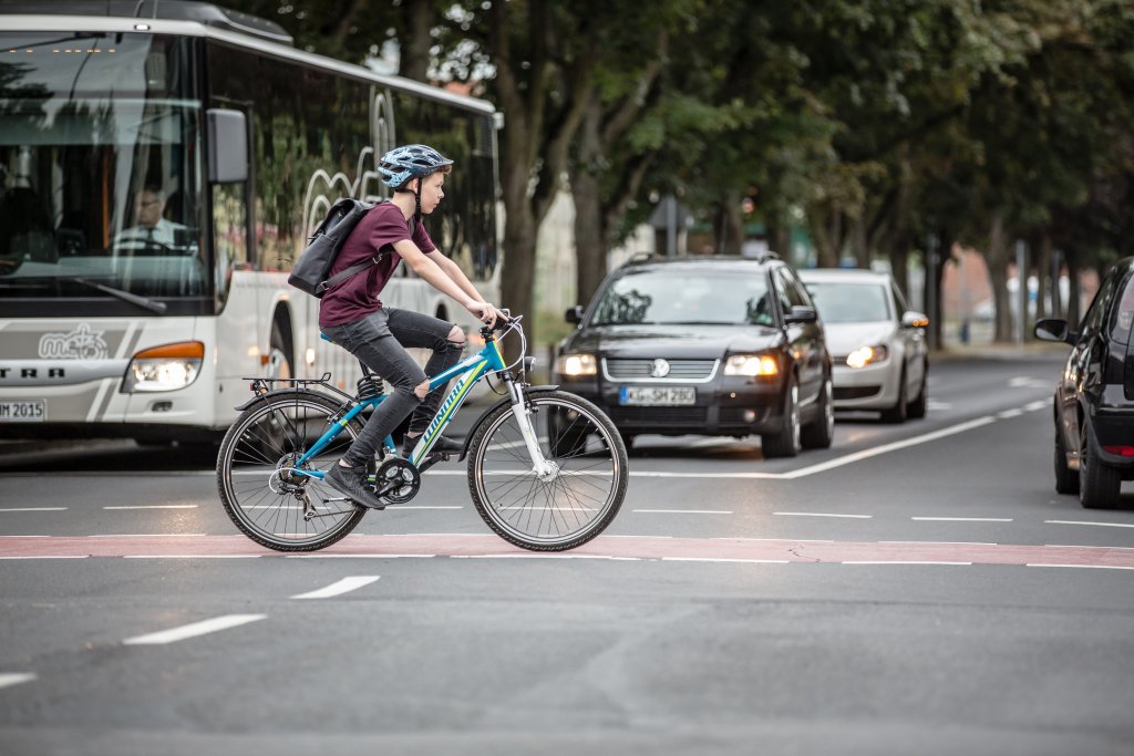 Ein Junge überquert auf einem Fahrrad eine Kreuzung.
