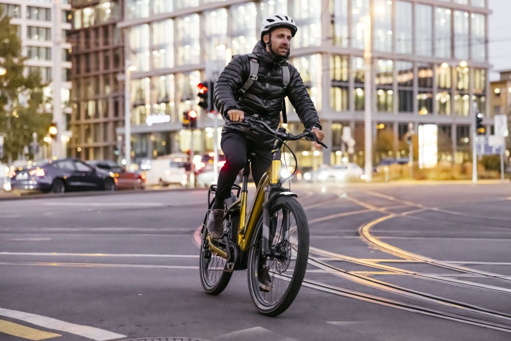 Ein Mann fährt auf einem E-Bike über eine Straßenkreuzung mit Straßenbahnschienen.