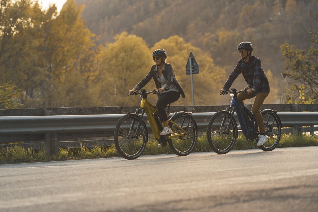 Paar fährt auf E-Bikes auf der Landstraße.