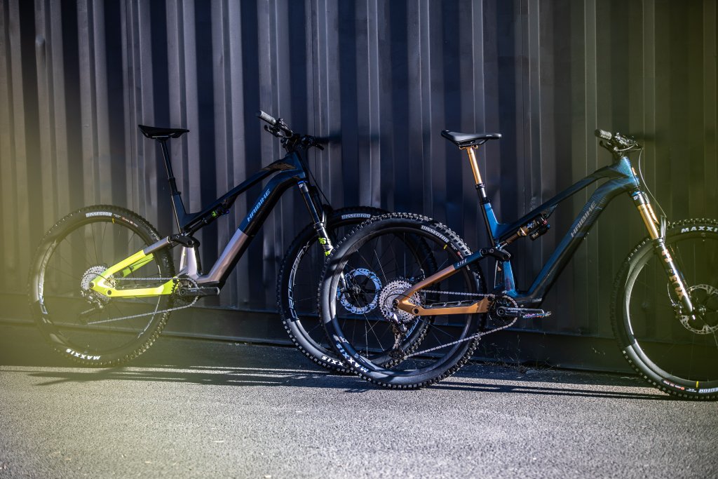 Zwei E-Mountainbikes lehnen an einer Metallwand.