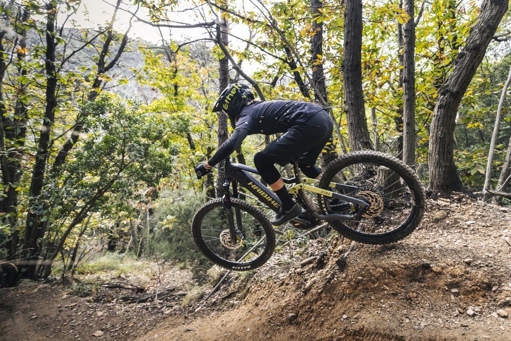 Eine Person spring auf einem E-MTB einen abschüssigen Teil einer Mountainbike-Strecke hinunter.
