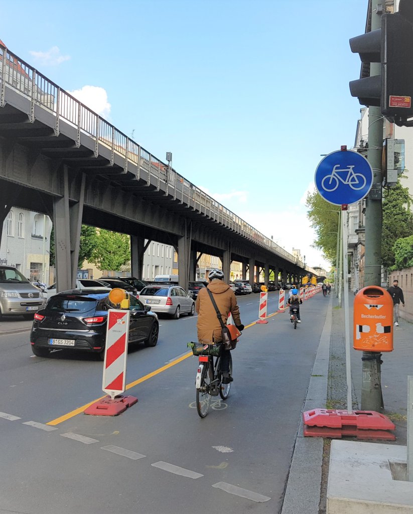 Eine Person fährt mit einem Fahrrad auf einem Bereich einer Straße, der mit Leitbaken von Autospuren getrennt ist.