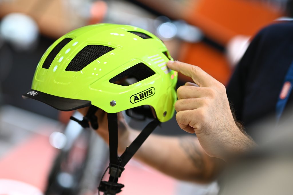 Eine Person präsentiert einen Fahrradhelm in Neongelb.