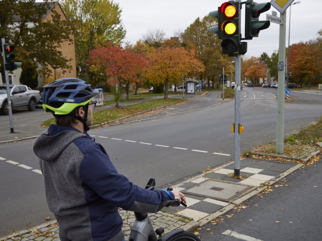 Ein Radfahrer steht an einer Ampel, die gerade umschaltet.
