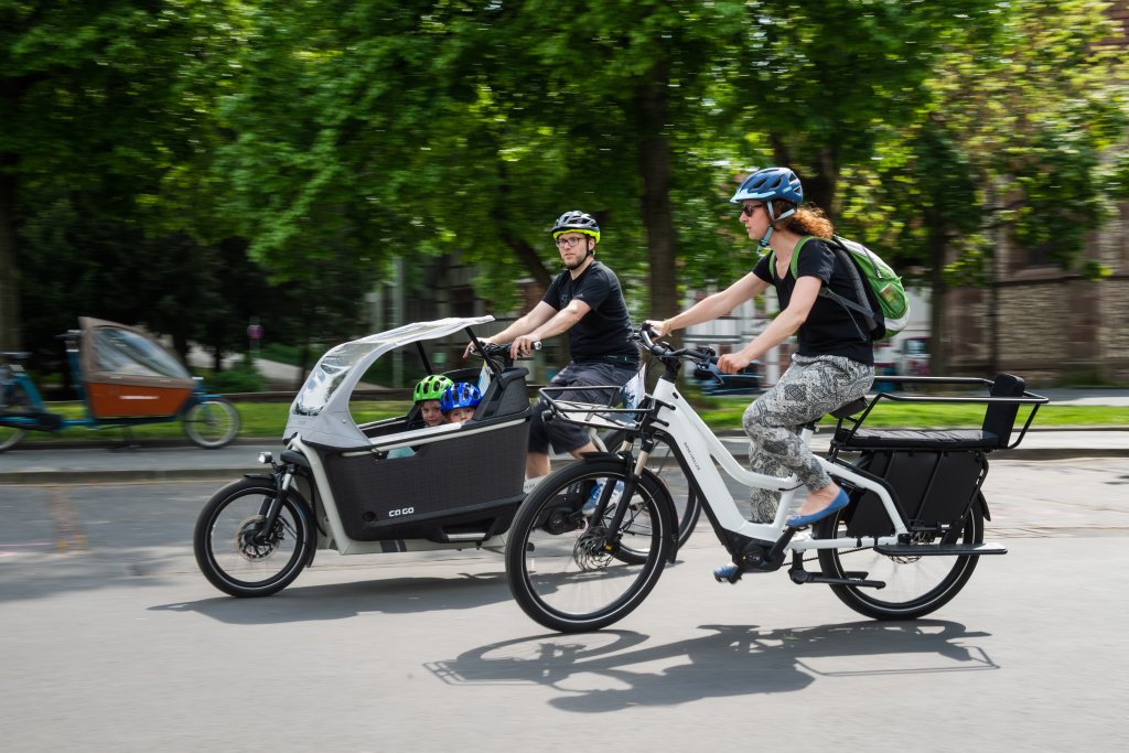 Zwei Personen auf Lastenrädern fahren nebeneinander.