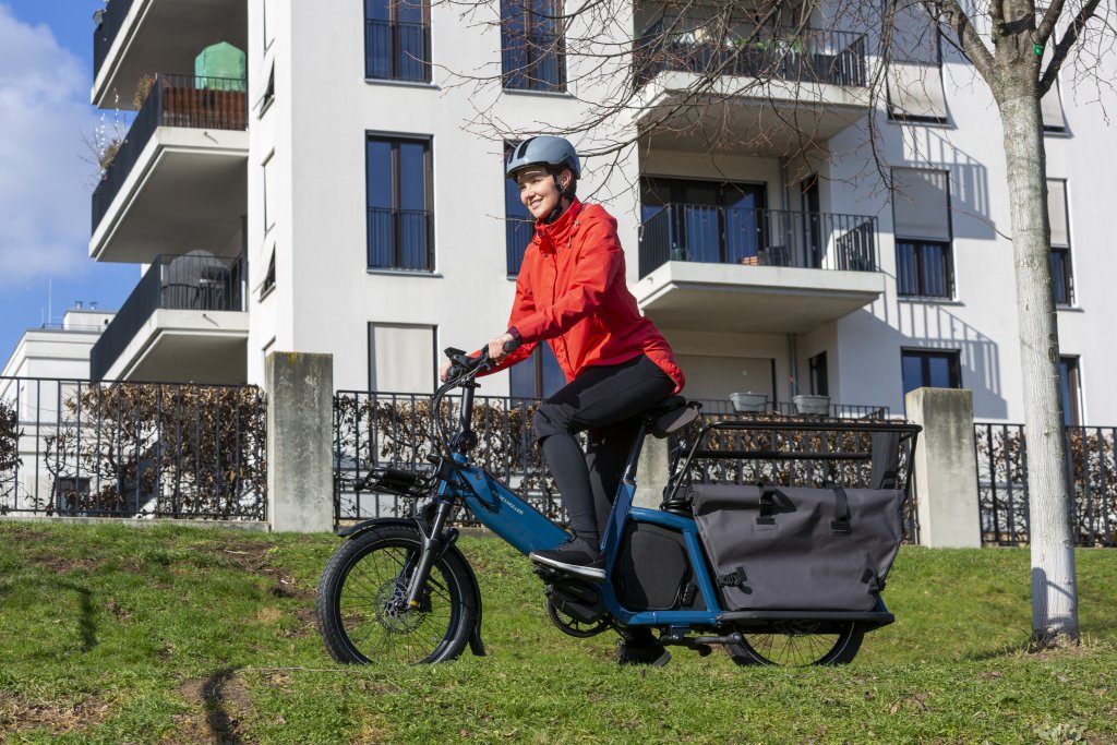 Frau fährt Lastenrad vor Wohnhaus