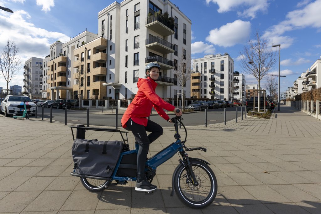 Frau fährt mit Lastenrad in der Stadt
