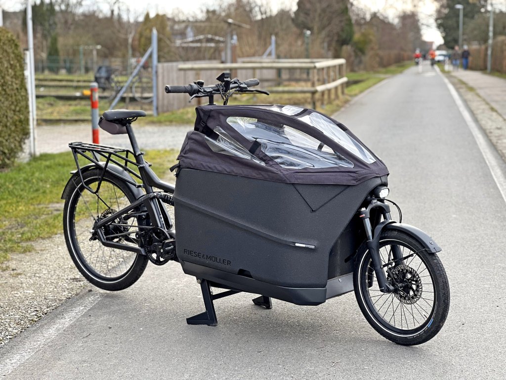 Ein Lastenrad mit verkleidetem Laderaum auf einer Fahrbahn.