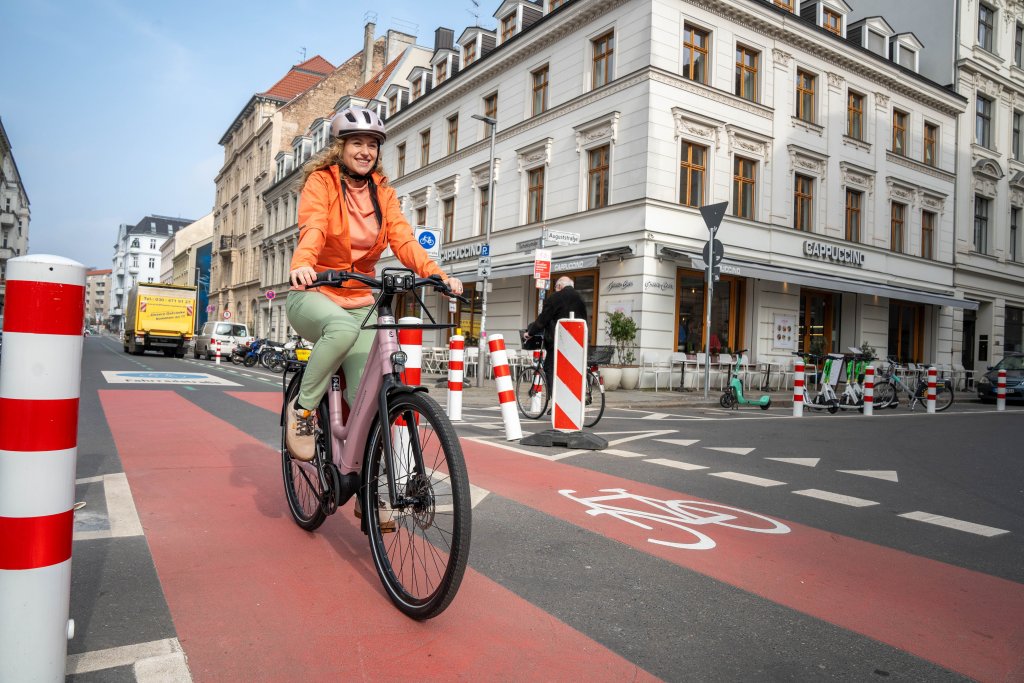 Eine Frau fährt auf einem E-Bike auf einer Radspur durch die Stadt.