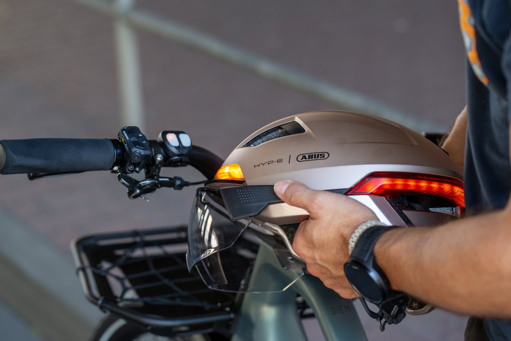 Mann hält einen Fahrradhelm mit Blinkfunktion in der Hand.
