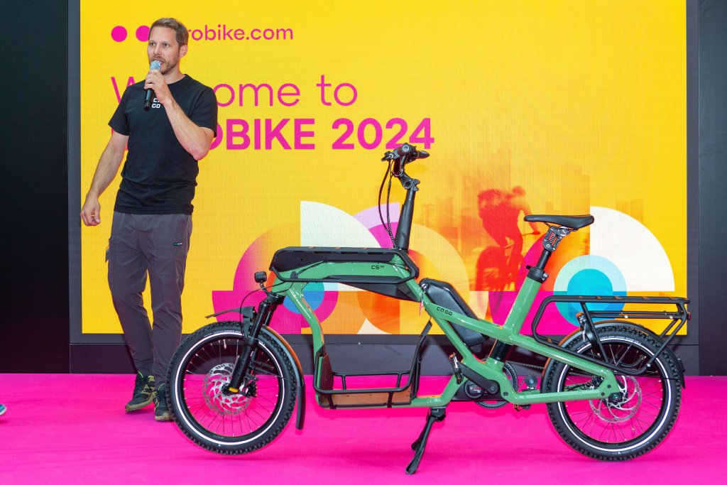 Mann auf einer Bühne auf der Eurobike präsentiert ein Cargobike.