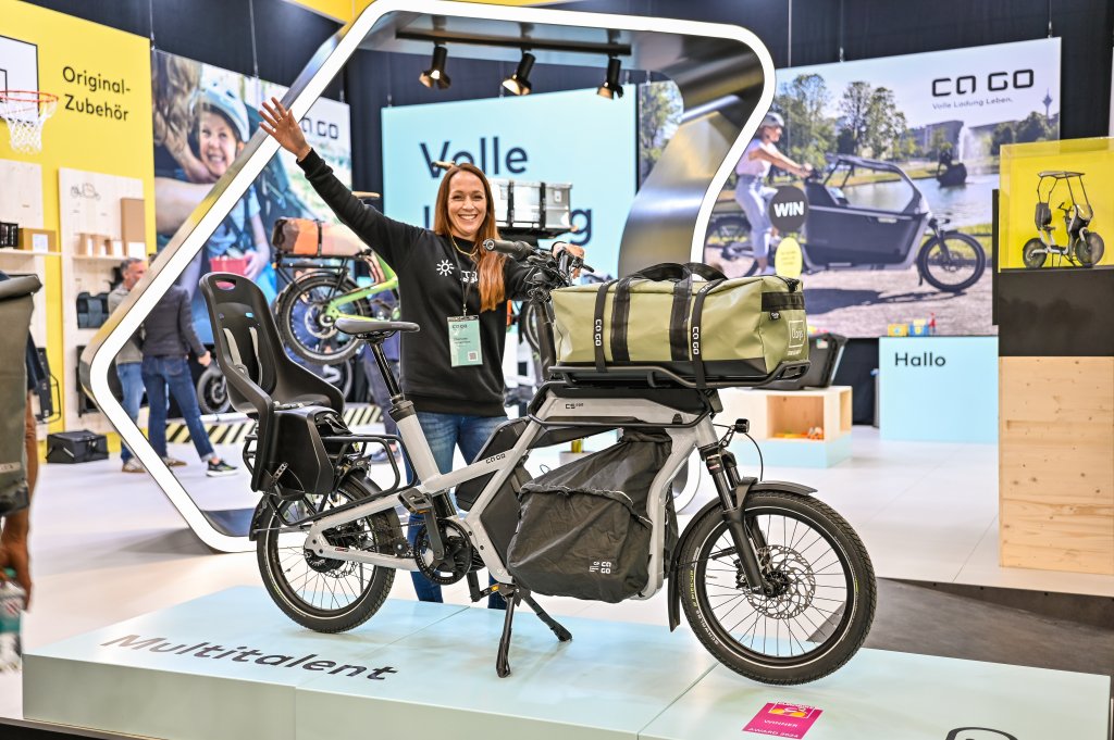 Frau steht neben einem vollbeladenen Cargobike auf der Fahrradmesse Eurobike.