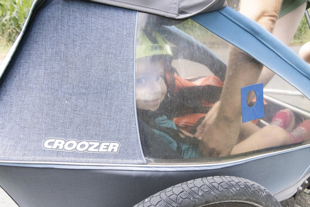 Kind mit Helm sitzt in Anhänger