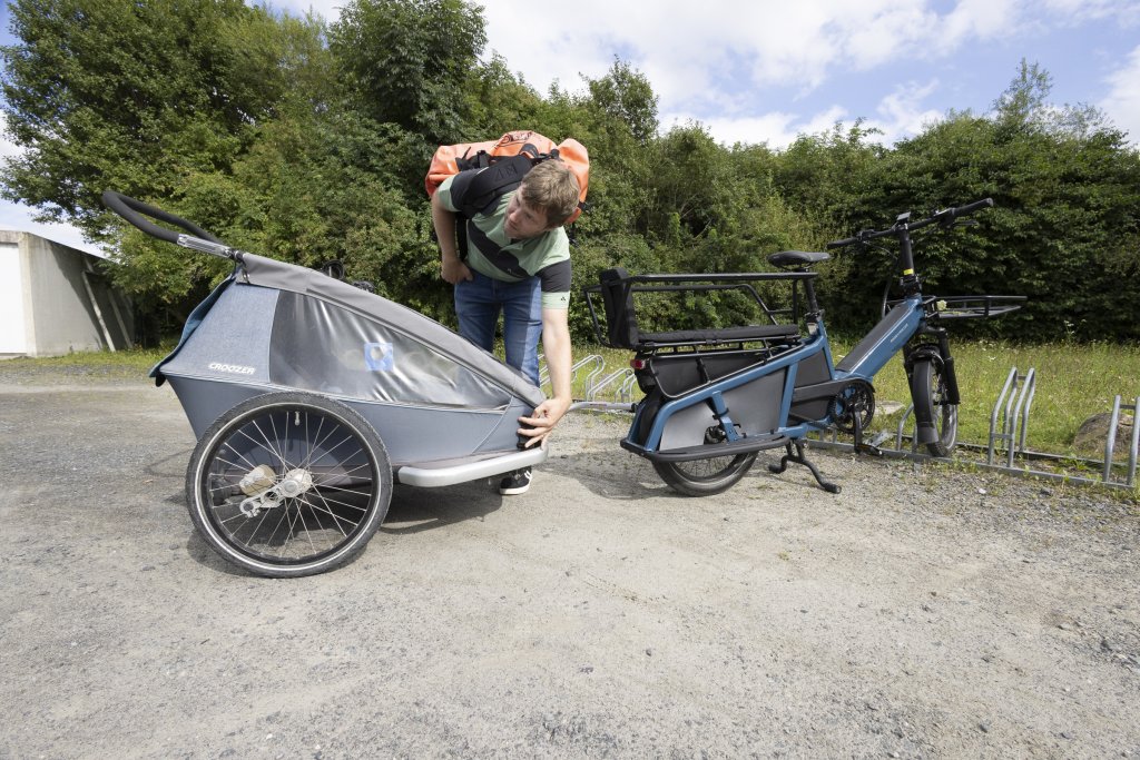 Longtail-Lastenrad mit Anhänger an Fahrradstellplatz.