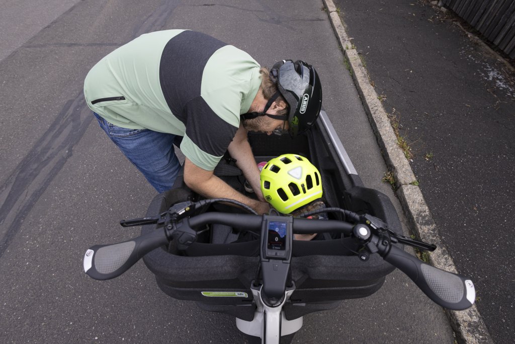 Mann schnallt Kind im Lastenrad an.
