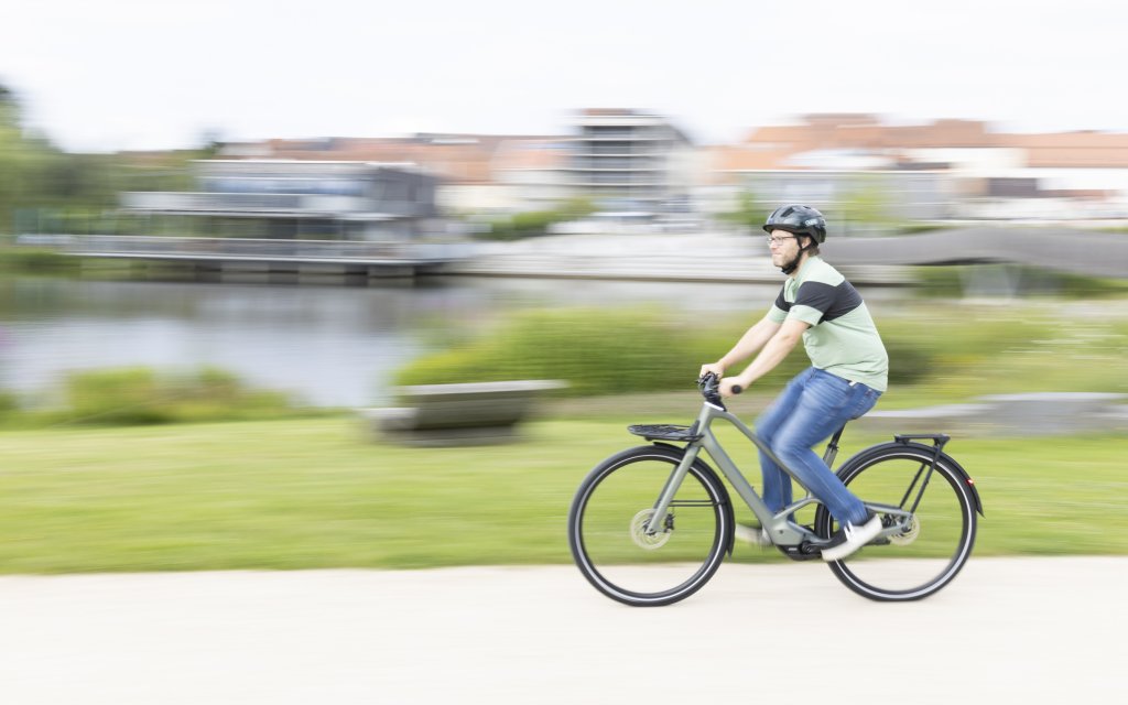 Mann fährt auf E-Bike durch einen Park.