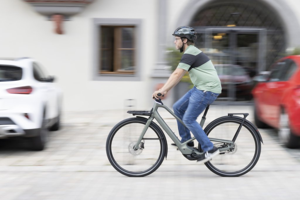 Mann fährt mit E-Bike durch Stadt.