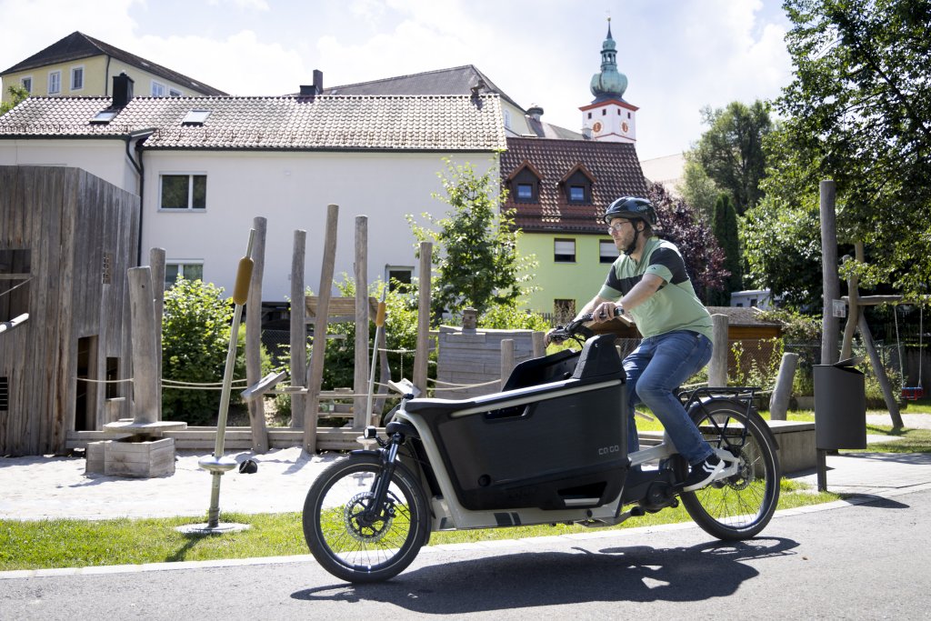 Mann fährt mit Lastenrad an Spielplatz vorbei