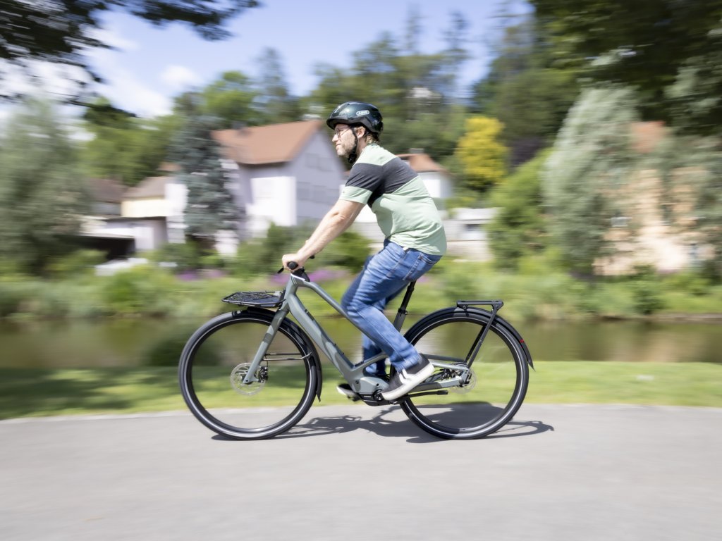 Mann fährt mit E-Bike an einem Fluss entlang.