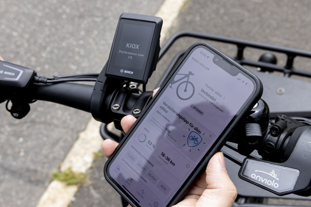 Hand hält Smartphone mit App an Fahrrad.