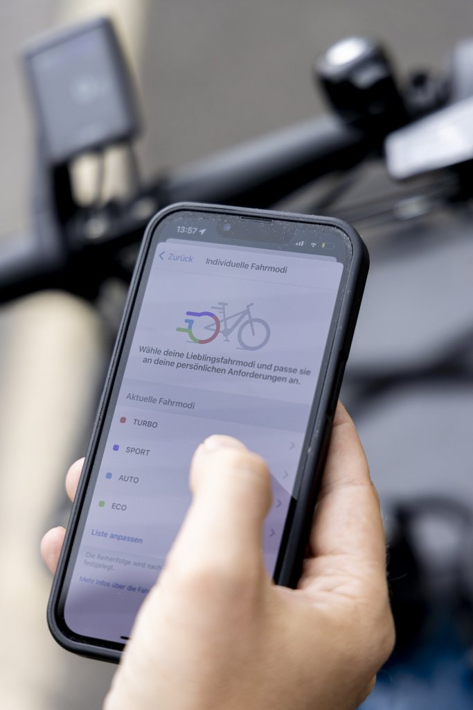 Hand hält Smartphone an E-Bike.