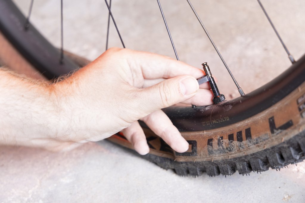 Hand schraubt an Fahrradventil.