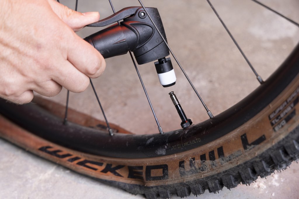 Pumpenkopf wird an Fahrradventil gehalten.