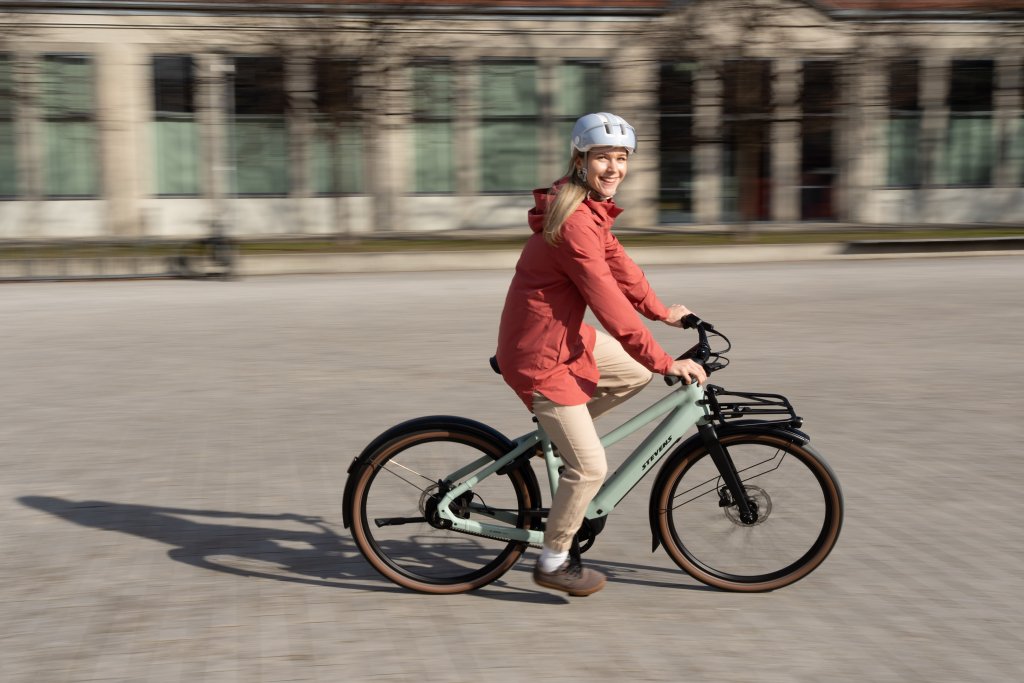 Frau fährt mit E-Bike über einen Platz.