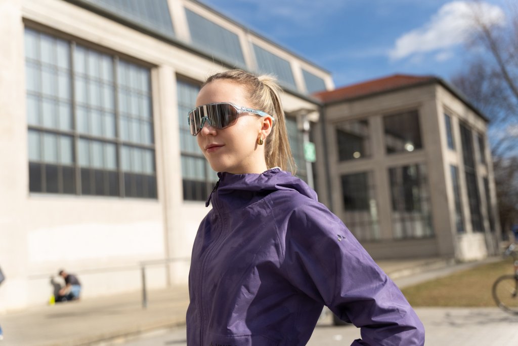 Frau mit Sonnenbrille steht in der Sonne.