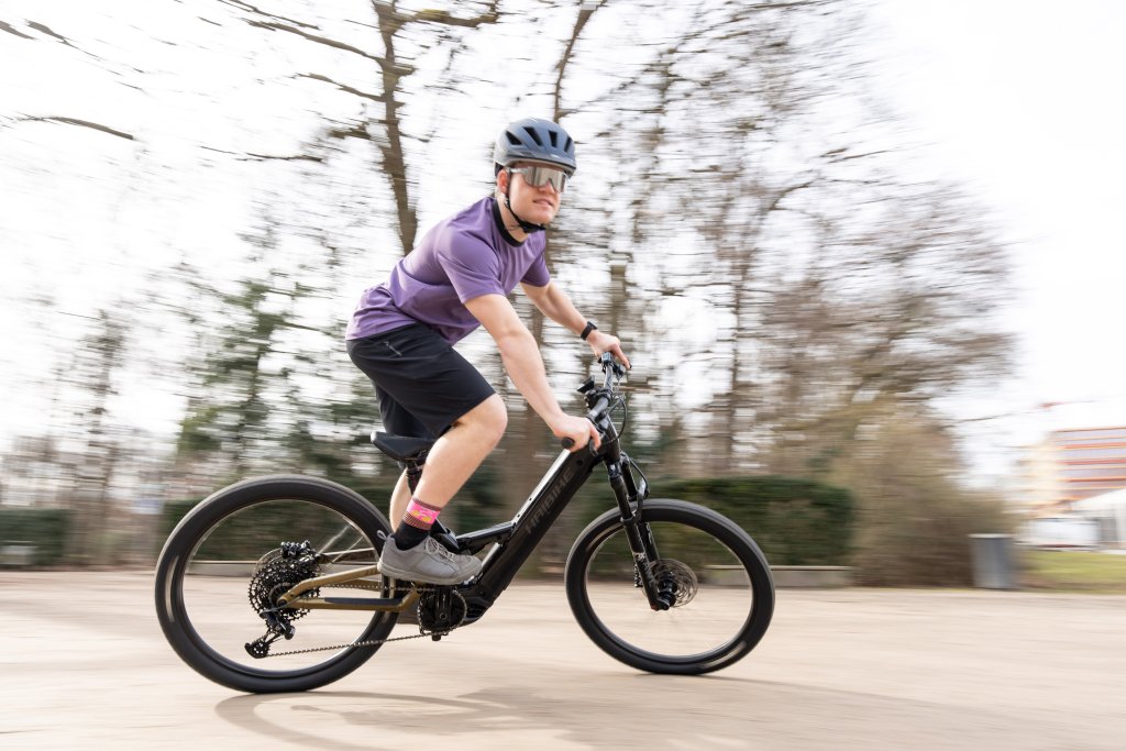 Mann fährt auf E-Mountainbike durch einen Park.